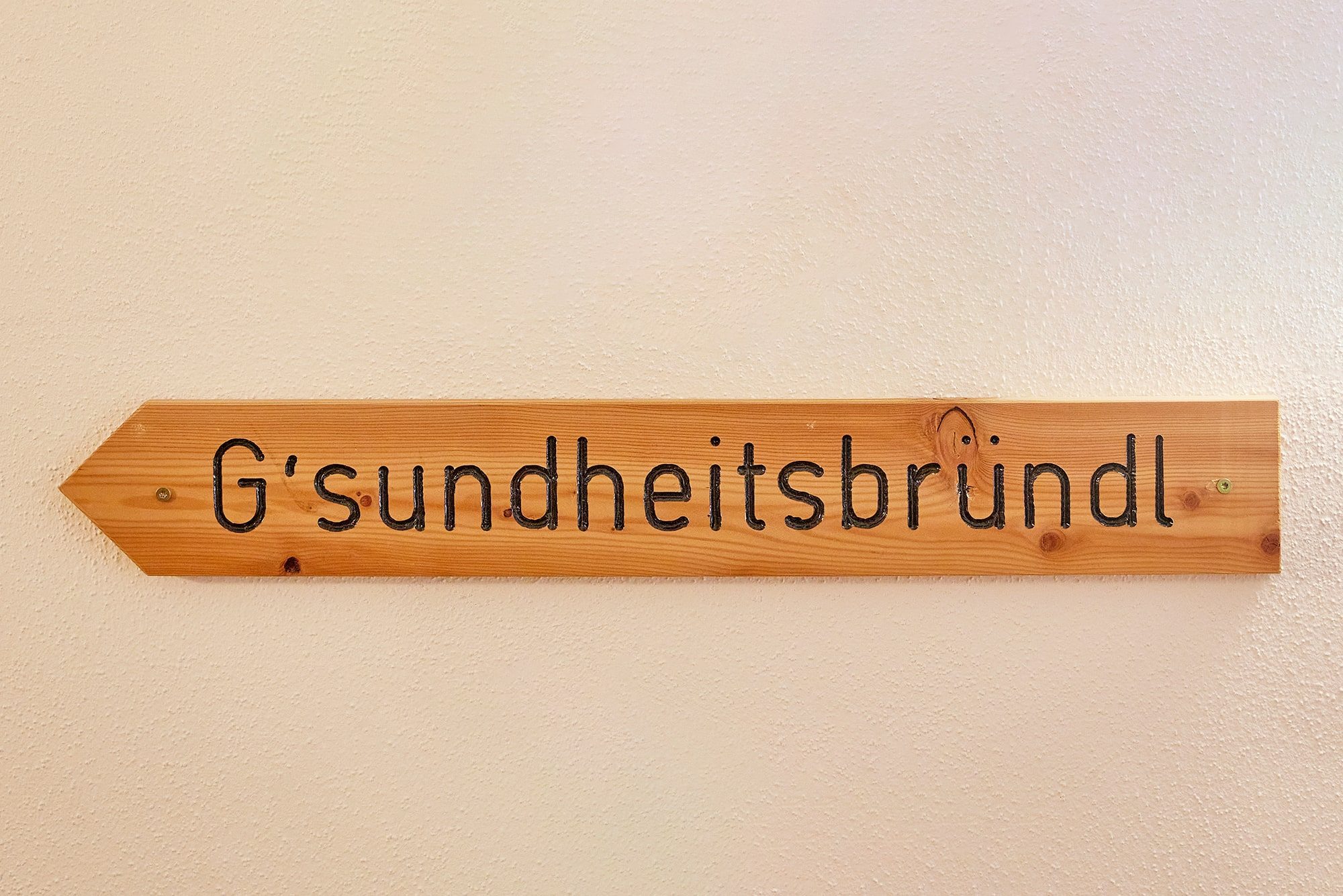 G’sundheitsbründl – hölzerner Wegweiser mit dem Namen des Appartements